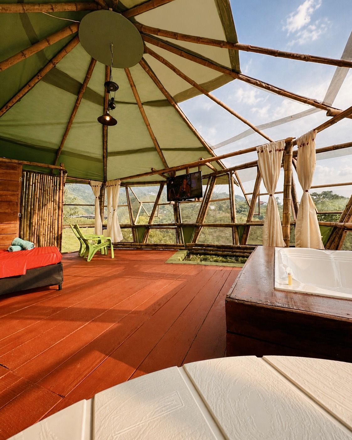 Interior de un domo con cama y ventanales hacia la terraza.