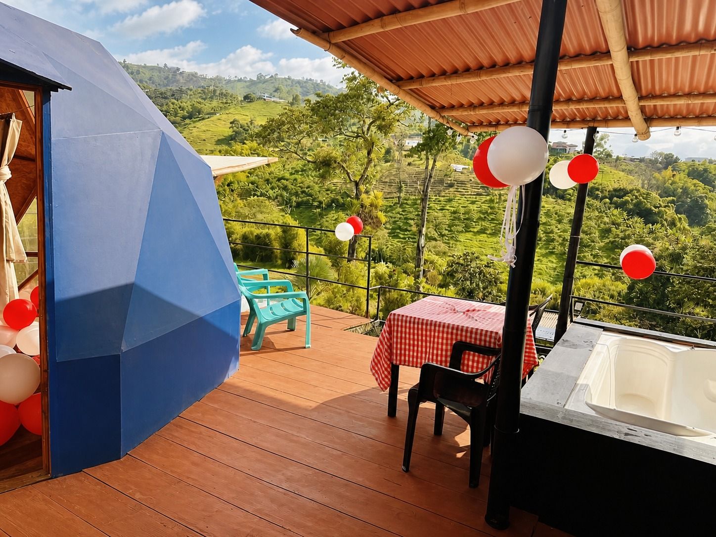 Terraza exterior con mesa y sillas junto a un domo; vegetación al fondo.